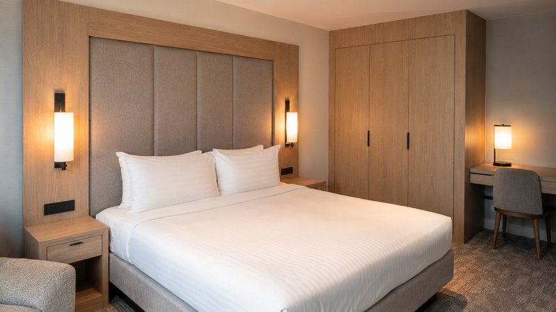Habitación de hotel con cabecero, armario y mesillas revestidos