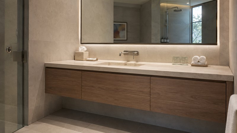 Baño de hotel con frente de mueble revestido en madera